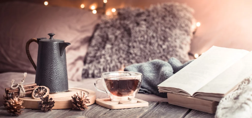 Ambiance cocooning avec tasse de thé fumante, théière en fonte et livre ouvert pour le blog GreenSip